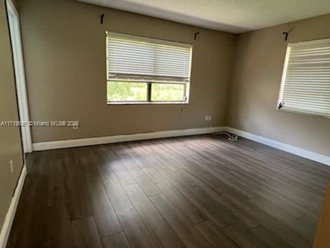 empty room featuring a textured ceiling and dark wood-type flooring