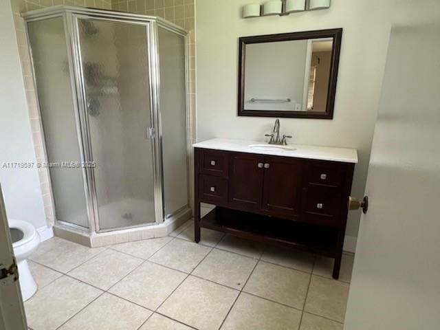 bathroom featuring tile patterned floors, vanity, toilet, and a shower with shower door