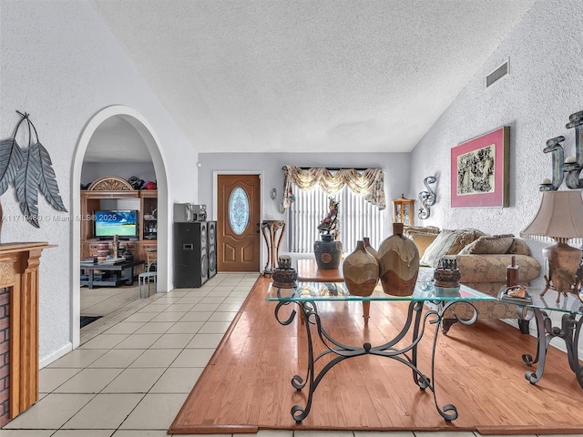 living room with light tile patterned flooring, lofted ceiling, and a textured ceiling