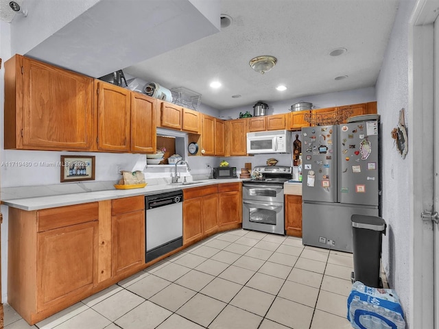 kitchen with sink, light tile patterned floors, a textured ceiling, and appliances with stainless steel finishes