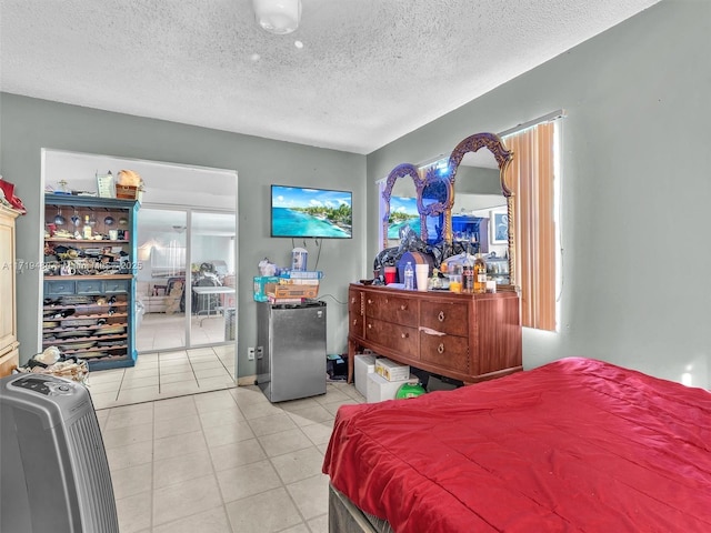 bedroom featuring stainless steel fridge, light tile patterned flooring, and a textured ceiling