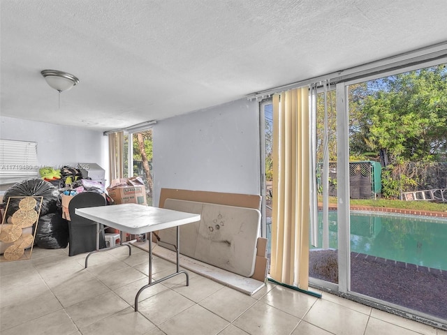 interior space with light tile patterned floors, a textured ceiling, and floor to ceiling windows