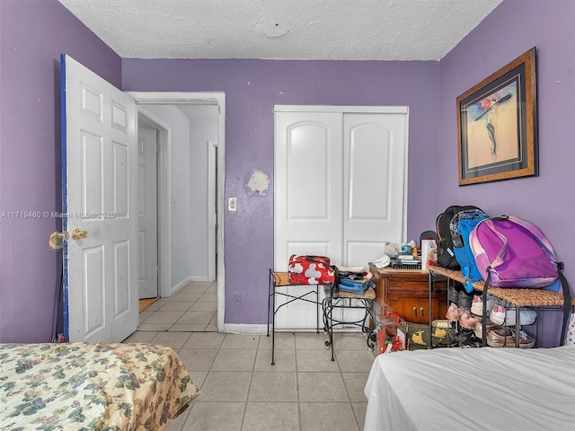 bedroom with a textured ceiling, a closet, and light tile patterned flooring