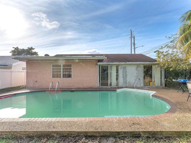 back of property with a fenced in pool