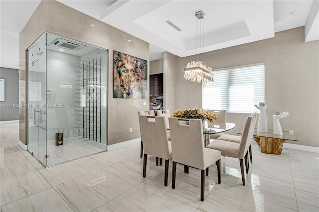 dining space with an inviting chandelier and a tray ceiling