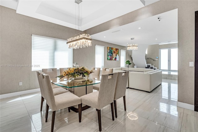 dining room with a raised ceiling, french doors, and an inviting chandelier