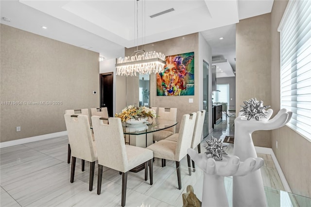 dining space featuring a raised ceiling and an inviting chandelier