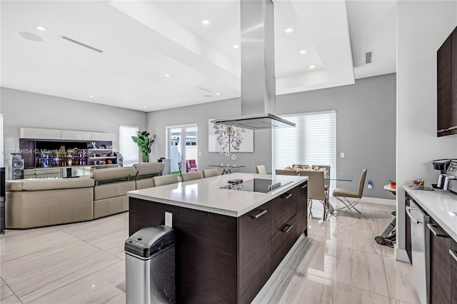 kitchen featuring dark brown cabinetry, black electric cooktop, a raised ceiling, island range hood, and a kitchen island