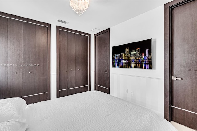 bedroom featuring a notable chandelier and multiple closets