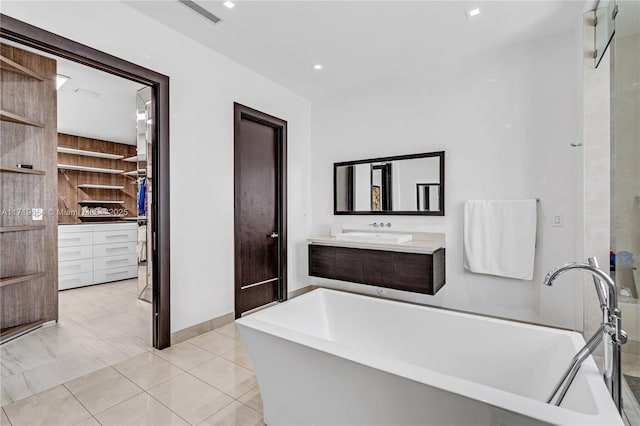 bathroom featuring tile patterned flooring, a bath, and vanity