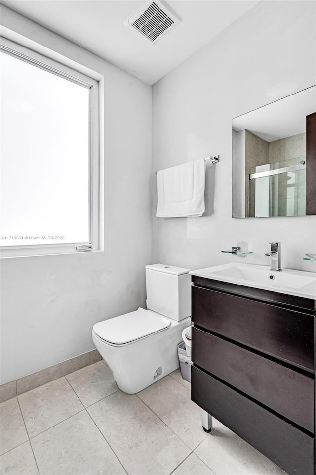 bathroom featuring tile patterned flooring, vanity, an enclosed shower, and toilet