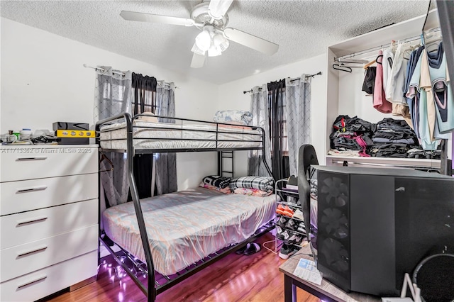 bedroom with ceiling fan, wood-type flooring, and a textured ceiling