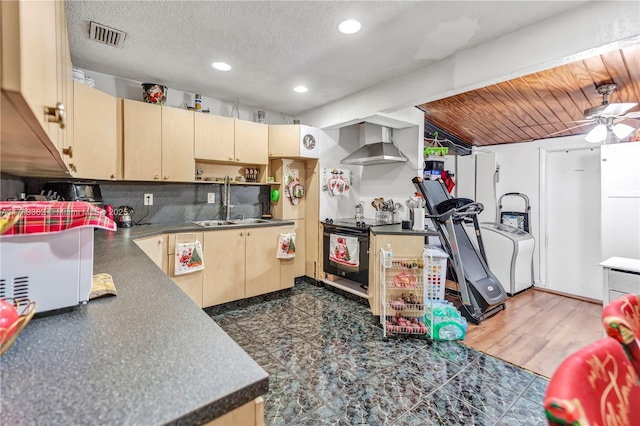 kitchen with stove, wall chimney range hood, sink, a textured ceiling, and light brown cabinetry