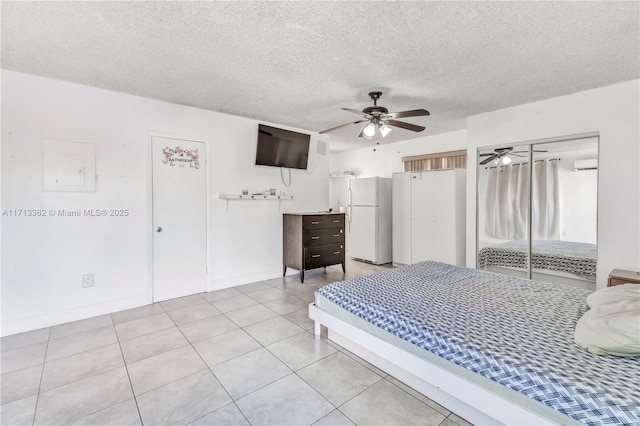 bedroom featuring a textured ceiling, ceiling fan, white refrigerator, a closet, and light tile patterned flooring