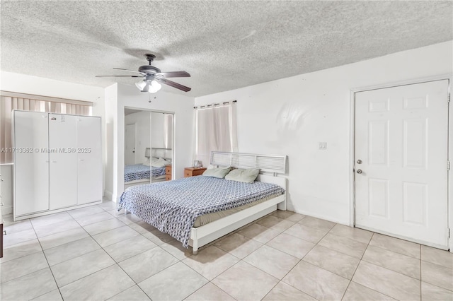 bedroom with ceiling fan, light tile patterned floors, and a textured ceiling