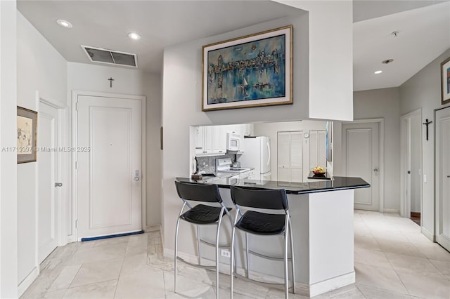 kitchen with kitchen peninsula, white cabinetry, a breakfast bar, and white appliances