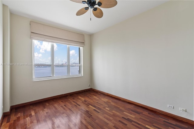 spare room with ceiling fan, dark hardwood / wood-style flooring, and a water view