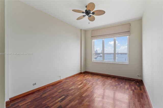 spare room featuring a water view, hardwood / wood-style flooring, and ceiling fan