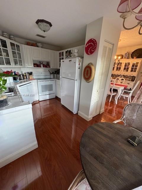 kitchen with tile countertops, dark wood-type flooring, range, white fridge, and white cabinetry