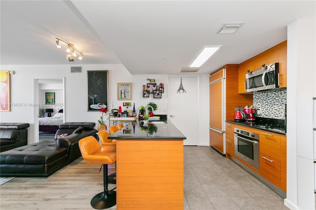 kitchen featuring a breakfast bar, sink, tasteful backsplash, a center island, and appliances with stainless steel finishes