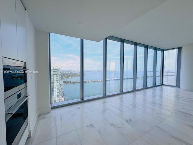 unfurnished living room with floor to ceiling windows, a water view, and a healthy amount of sunlight