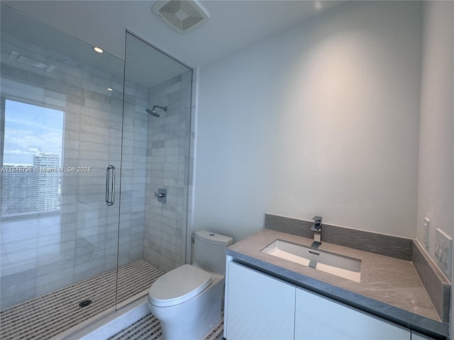 bathroom featuring a shower with door, vanity, and toilet