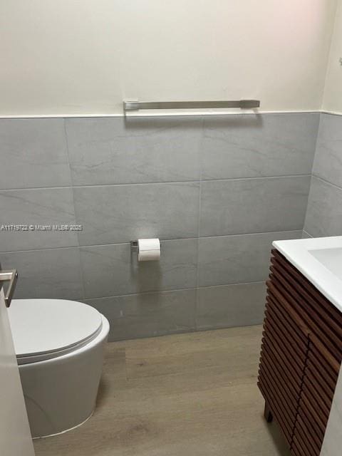 bathroom with vanity, hardwood / wood-style flooring, toilet, and tile walls