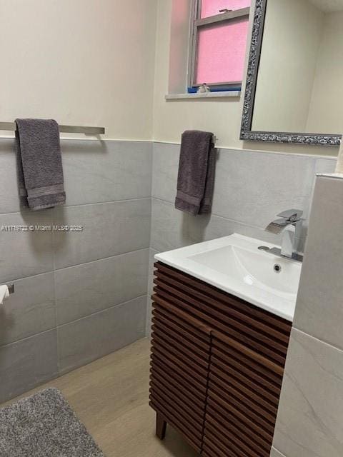 bathroom featuring hardwood / wood-style floors, vanity, and tile walls