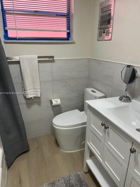 bathroom with hardwood / wood-style flooring, vanity, toilet, and tile walls