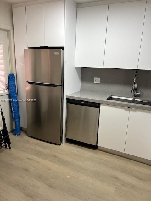 kitchen with white cabinetry, sink, stainless steel appliances, and light hardwood / wood-style floors