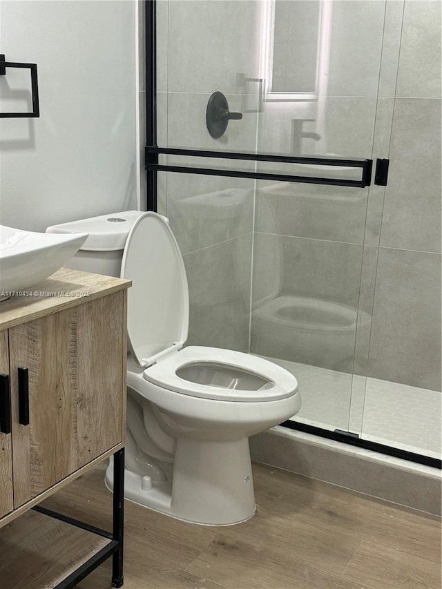 bathroom with wood-type flooring, toilet, and a shower with shower door