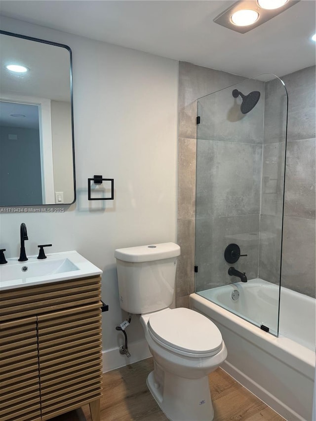 full bathroom with vanity, tiled shower / bath combo, hardwood / wood-style flooring, and toilet