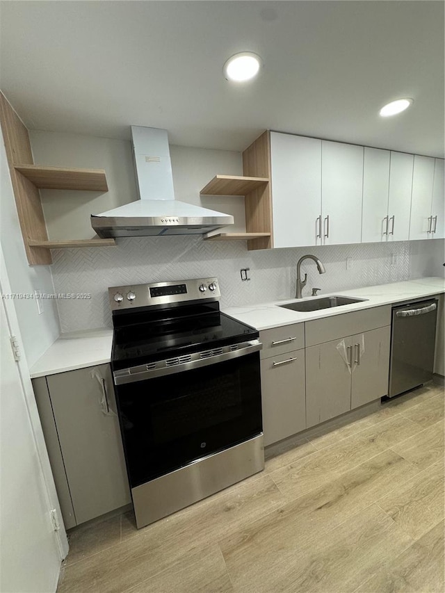 kitchen featuring extractor fan, a sink, light countertops, appliances with stainless steel finishes, and open shelves