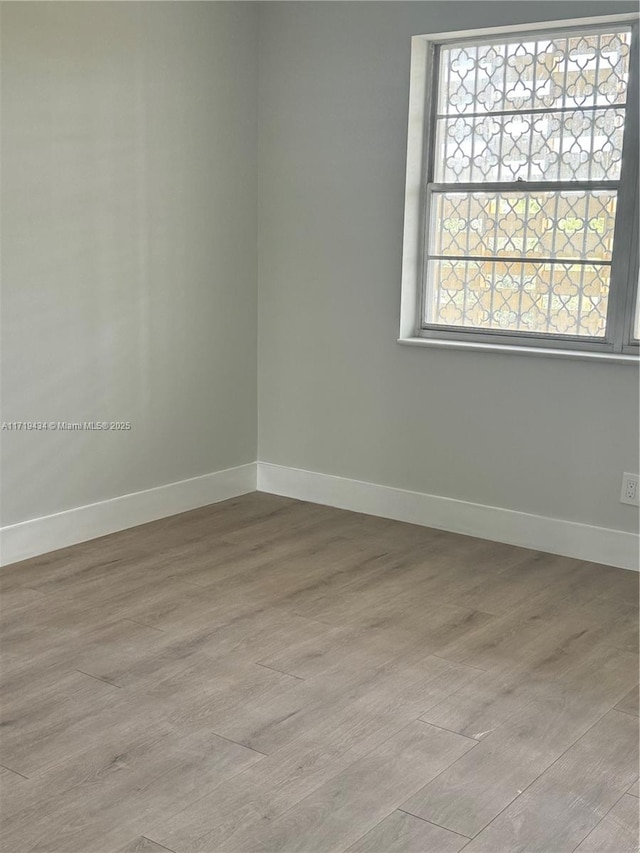 empty room featuring light wood-type flooring and baseboards