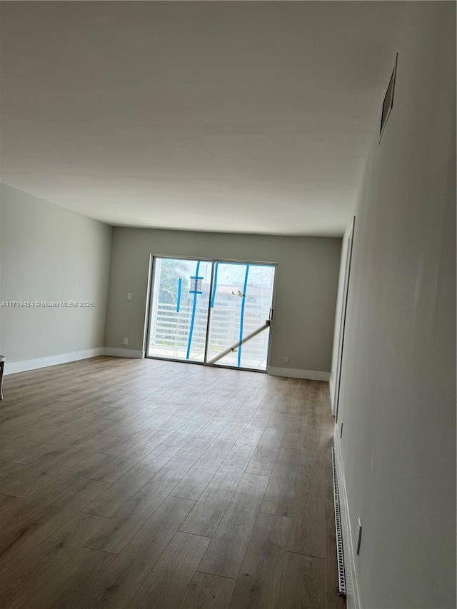 spare room with dark wood-style flooring, visible vents, and baseboards