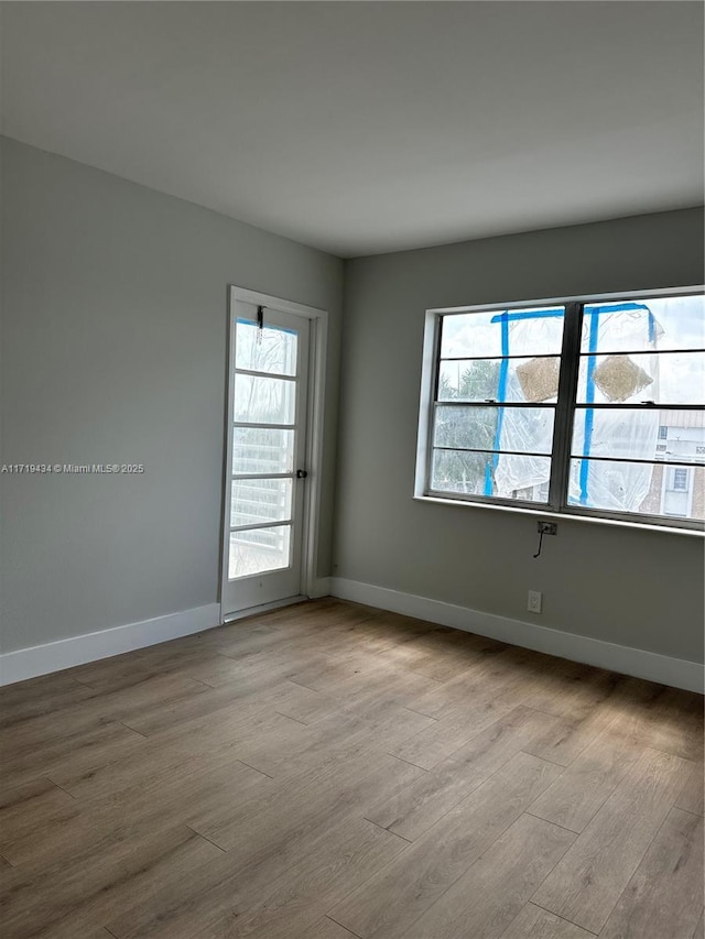 spare room with baseboards and wood finished floors