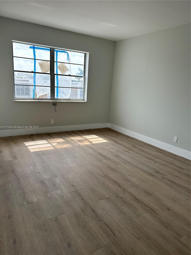 empty room with baseboards and wood finished floors