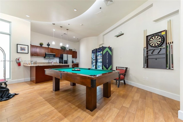 recreation room featuring a towering ceiling, sink, billiards, and light wood-type flooring