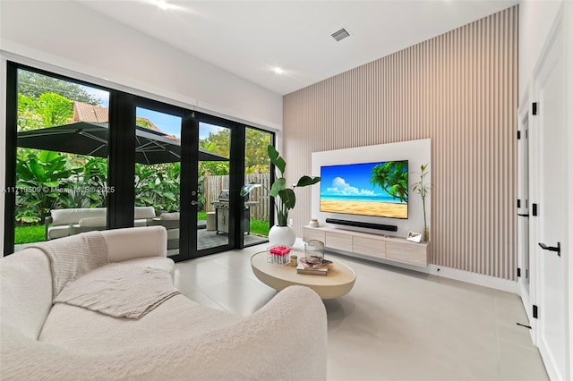 living room featuring wood walls, a healthy amount of sunlight, light tile patterned floors, and french doors