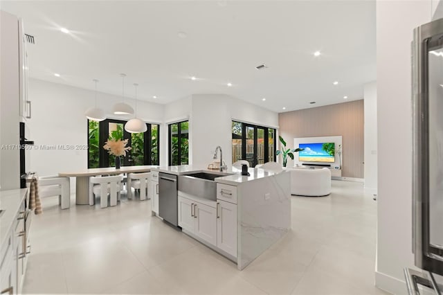 kitchen with light stone countertops, dishwasher, pendant lighting, a kitchen island with sink, and white cabinets