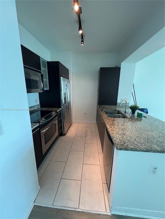 kitchen with sink, rail lighting, kitchen peninsula, light tile patterned floors, and appliances with stainless steel finishes