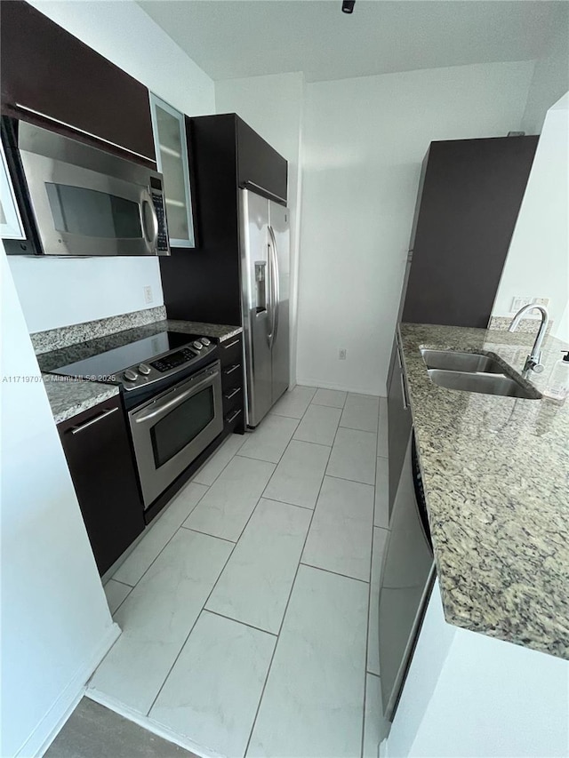 kitchen featuring light stone counters, sink, and appliances with stainless steel finishes