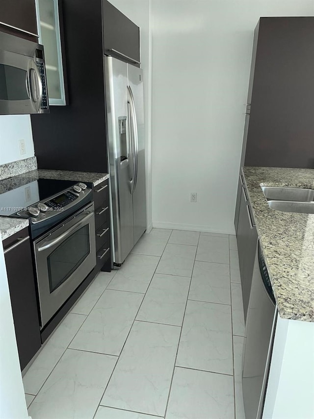 kitchen featuring light stone counters, sink, and appliances with stainless steel finishes