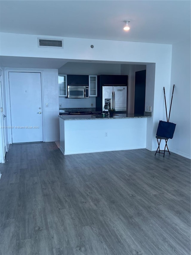 kitchen with dark hardwood / wood-style floors, kitchen peninsula, and appliances with stainless steel finishes