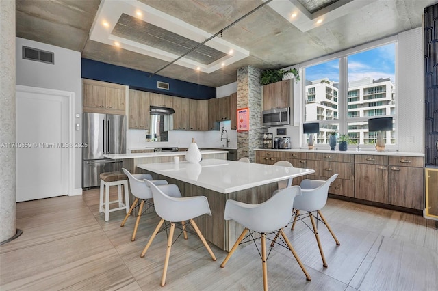 kitchen featuring sink, a center island, a kitchen breakfast bar, floor to ceiling windows, and appliances with stainless steel finishes