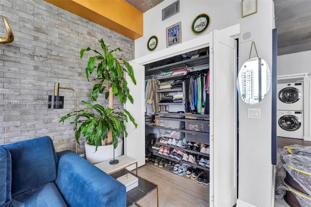 spacious closet with stacked washer and dryer and wood-type flooring