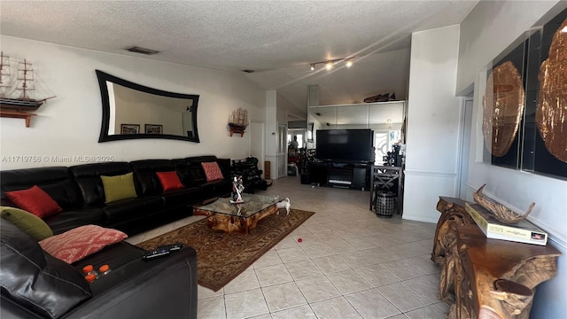 living room with vaulted ceiling, a textured ceiling, and light tile patterned flooring