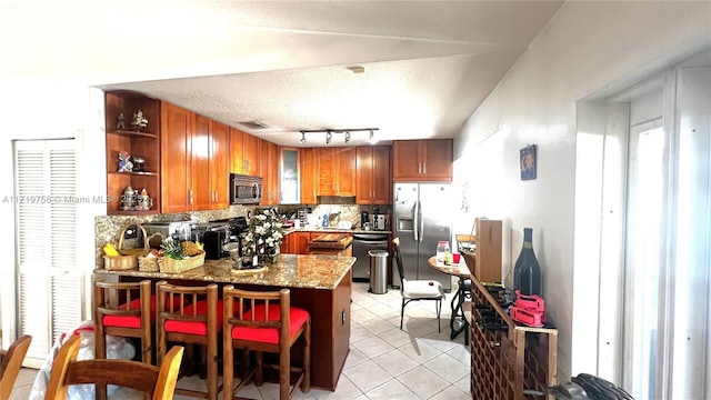 kitchen featuring appliances with stainless steel finishes, backsplash, kitchen peninsula, light stone counters, and light tile patterned floors