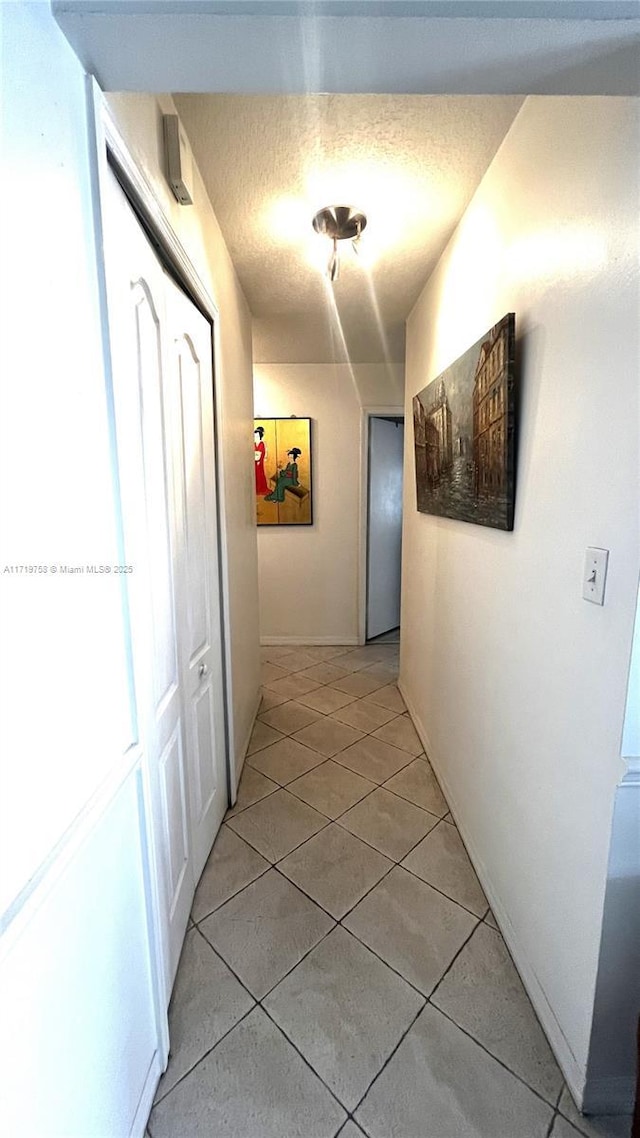 corridor featuring a textured ceiling and light tile patterned floors