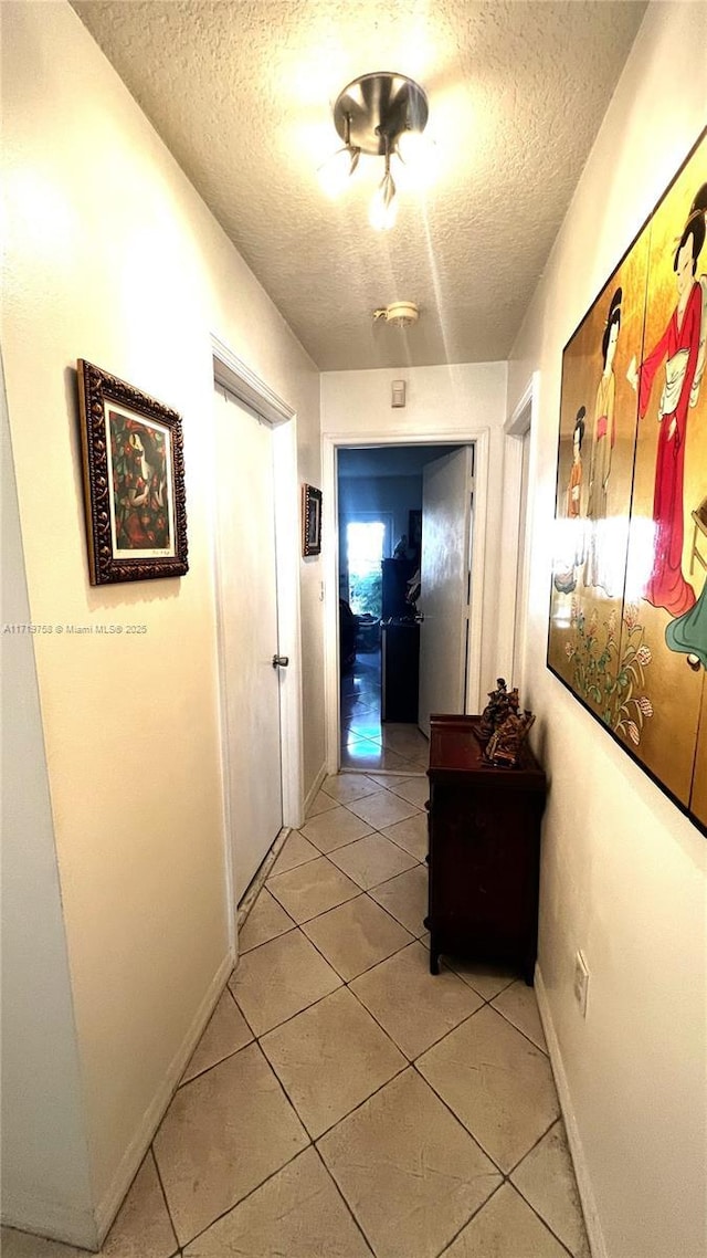 corridor with light tile patterned floors and a textured ceiling